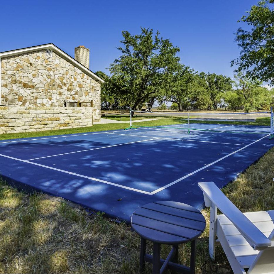 Existing pickleball court, limestone clubhouse, and oak trees at Open Air Spicewood